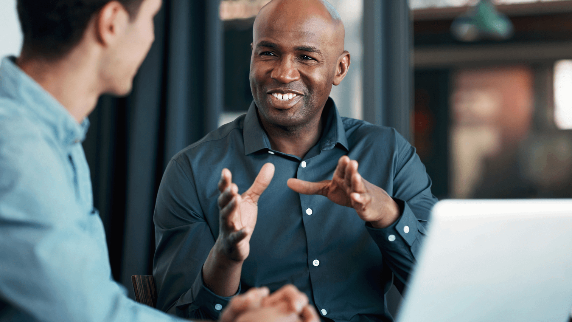 Two men at a desk smiling and in discussion