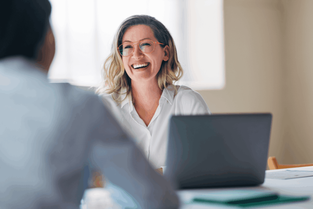 Woman laughing with colleague at desk